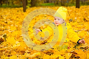 Happy adorable child girl with leaves in autumn park. Fall.The concept of childhood