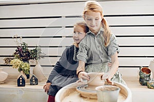 Happy adorable children making a pottery on pottery wheel