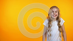 Happy adorable girl laughing, standing on orange background, humor and jokes