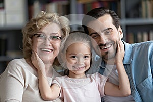 Happy adorable kid girl cuddling older granny and young father.