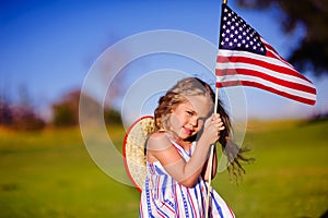 Happy adorable little girl smiling and waving American flag outs