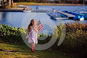 Happy adorable little girl smiling and waving American flag outs