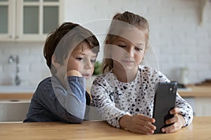 Happy adorable little kids playing cellphone at home.