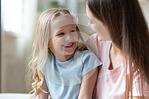 Happy adorable little preschool girl talking with positive mommy.