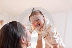 Happy adorable newborn baby playing with mom on bed smiling and cheerful at cozy home.Mom talking with infant baby laughing