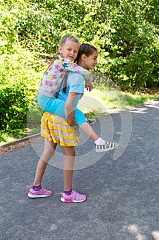 Happy adorable preschool girl on a piggy back ride with her elder sister