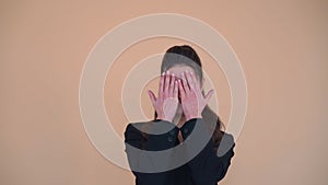 Happy adorable woman with brunette hair in black jacket opening and covering her face with hands, playing hide and seek