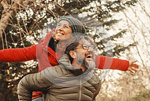 Happy adult couple of tourist have fun and enjoy outdoor leisure activity playing and laughing a lot. One man carrying woman in