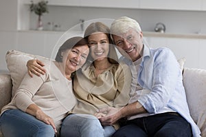 Happy adult daughter enjoying meeting with senior parents at home