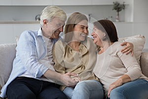 Happy adult daughter enjoying meeting with senior parents at home