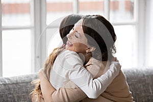 Happy adult daughter and old mom hug at home