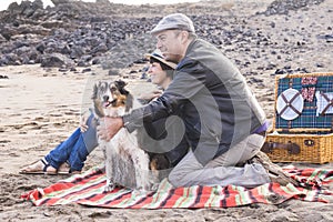 Happy adult family people stay together at the beach with adorable funny dirty dog - happiness and outdoor leisure activity for