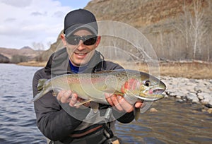 Happy adult fisherman holding steelhead trout