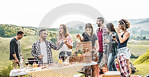 Happy adult friends eating at picnic lunch in italian vineyard outdoor - Young people having fun on gastronomic weekend tuscany