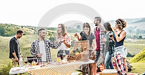 Happy adult friends eating at picnic lunch in italian vineyard outdoor - Young people having fun on gastronomic weekend tuscany photo
