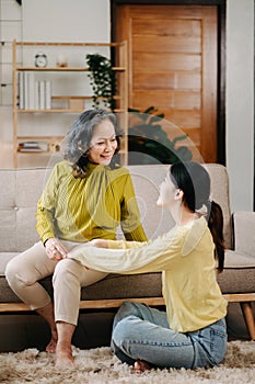 Happy adult granddaughter and senior grandmother having fun enjoying talk sit on sofa in living room at home