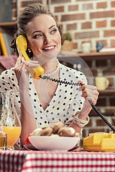 happy adult housewife talking by vintage wired phone