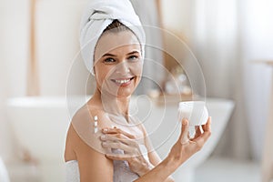 Happy adult lady using body lotion after shower