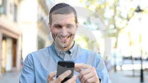 Happy adult man walking using smart phone in the street