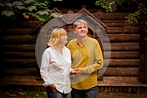 Happy,adult man and woman standing near an eco-friendly,wooden house on a Sunny day