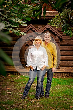 Happy,adult man and woman standing near an eco-friendly,wooden house on a Sunny day