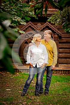 Happy,adult man and woman standing near an eco-friendly,wooden house on a Sunny day