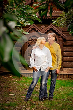 Happy,adult man and woman standing near an eco-friendly,wooden house on a Sunny day