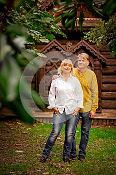 Happy,adult man and woman standing near an eco-friendly,wooden house on a Sunny day