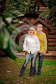 Happy,adult man and woman standing near an eco-friendly,wooden house on a Sunny day