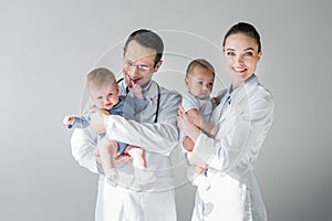 happy adult pediatricians holding little babies photo