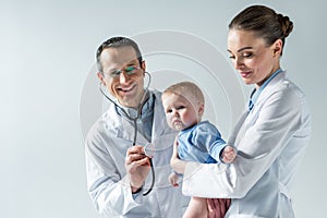 happy adult pediatricians taking care of little baby