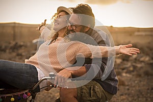 Happy adult people cheerful couple enjoy the outdoor leisure activity riding a bike together man carrying woman and laugh a lot in