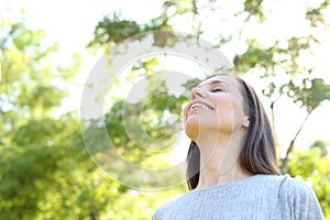 Happy adult woman breathing fresh air in a forest