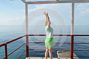 Happy adult woman doing gymnastics on the beach, back view, healthy lifestyle concept