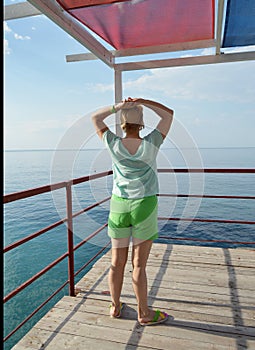 Happy adult woman doing gymnastics on the beach, back view, healthy lifestyle concept