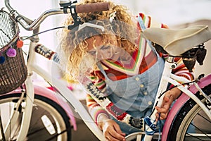 Happy adult woman at home in hobby work leisure activity indoor modify a female bike with piece of covers and full of colors -