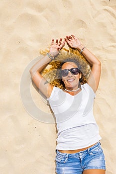 Happy adult woman lay donw on the sand beach enjoying summer sun and holiday vacation - one beautiful iddle age female people in