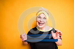 Happy adult woman smiling looking at the camera and holding an elastic band for training
