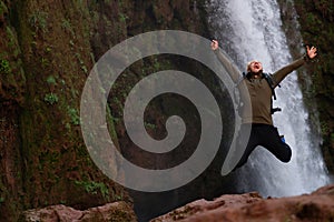 Happy adventurer jumping near Ouzoud waterfall in Morocco