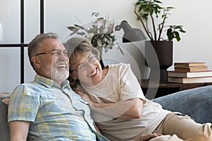 Happy affectionate 60s couple resting on sofa.