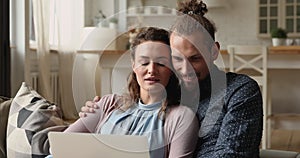 Happy affectionate bonding young married couple using computer.