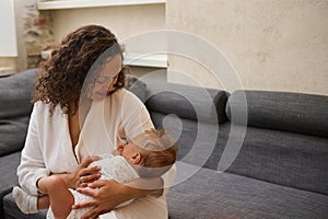 A happy affectionate mother holding a sleeping baby boy in her arms. Maternity leave lifestyle, Babyhood and infancy