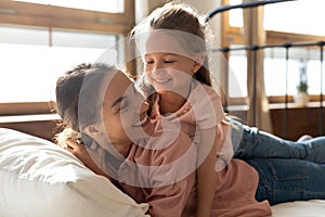 Happy affectionate mother and kid daughter laughing bonding on bed