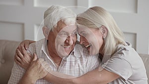 Happy affectionate senior old couple embracing bonding looking at camera