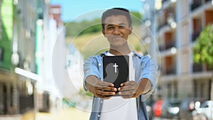 Happy african-american boy showing holy bible on camera and smiling, religion
