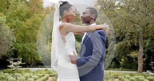 Happy african american bride and groom dancing at their wedding in garden, slow motion