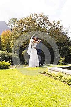 Happy african american bride and groom embracing at wedding in sunny garden, copy space