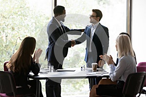 Happy African American business leader shaking hands with promoted employee