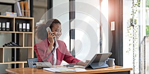 Happy african-american business woman talking on mobile at office. Young female manager consulting on phone, using