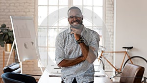 Happy african american businessman standing in modern office, business portrait